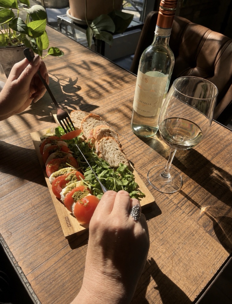 Caprese s rukolou a pečivom podávané k pohárku bieleho vína v bistre RODIN
