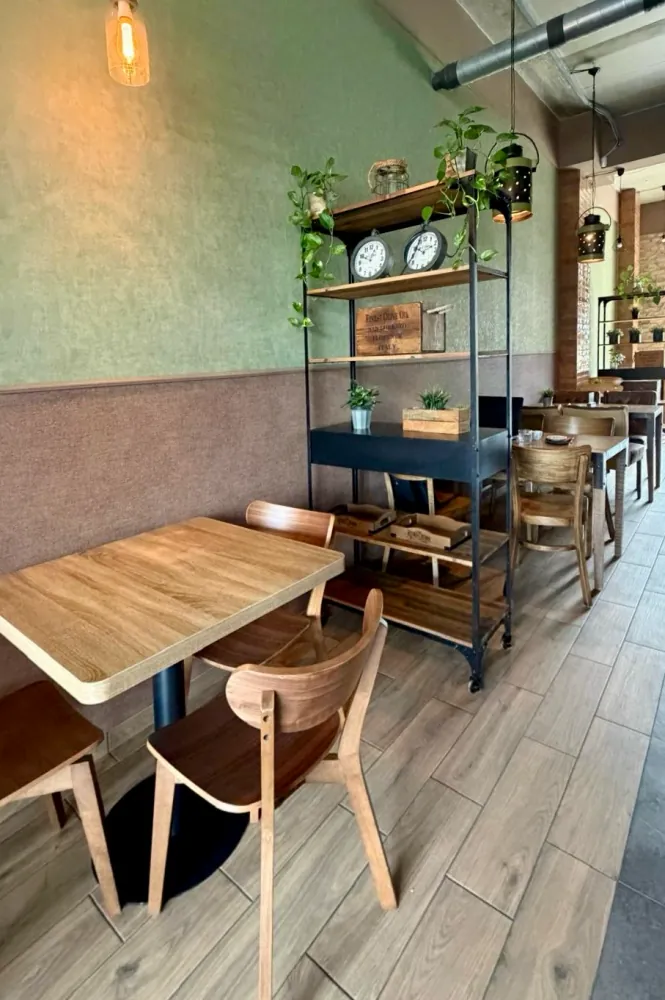 Coworking zóna RODIN – drevené stoly a regál s rastlinami pri zelenej stene